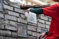 Asian worker installing glass block onto brick wall with mortar