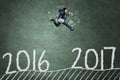 Asian worker jumps on blackboard with 2017