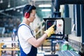 Asian worker operating CNC metal skip in factory