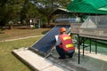 The Asian worker in uniform and helmet checks concentrating Solar Power with Flat Plat collector and Evacuum Tube Collector.