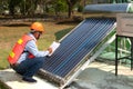 The Asian worker in uniform and helmet checks concentrating Solar Power with Flat Plat collector and Evacuum Tube Collector.