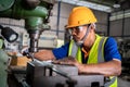 Asian worker uses a vernier measuring machine to inspect components for fabrication on a lathe at a factory