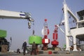 Asian workers with crane truck are working to transfer green lateral with red fairway buoys into the ship at harbor Royalty Free Stock Photo