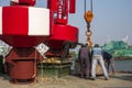 Asian workers working to remove red fairway buoys and large concrete anchor block into the ship