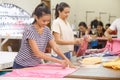 Asian workers marking a fabric and packaging their product