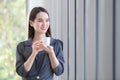 Asian working woman is looking out of window to think something while holding a coffee cup made of paper at the office Royalty Free Stock Photo