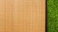 Asian woven wood or rattan mat on green grass texture background