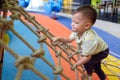 Asian 2 years old toddler baby boy child having fun trying to climb on jungle gym at indoor playground Royalty Free Stock Photo