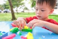 Asian 3 - 4 years old toddler baby child having fun playing colorful modeling clay / play dought at play school / child care