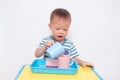 Asian 2 years old toddler boy child having fun pouring water into cup, Wet Pouring Montessori