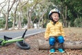 Asian 2 - 3 years old toddler boy child wearing safety helmet, sitting on a wooden log taking a break after riding his balance Royalty Free Stock Photo