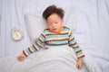 Asian 3 - 4 years old toddler boy kid taking a nap, sleeping on his back with alarm clock, The importance of sleep in child