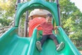 Asian 2 - 3 years old toddler boy playing on a slide in playground / school yard on summer sunny day on nature Royalty Free Stock Photo