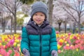 Asian 2 - 3 years old toddler boy smiling and looking at camera in Sakura cherry blossom and the tulips field park Royalty Free Stock Photo