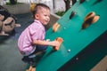 Asian 2 - 3 years old toddler child having fun trying to climb on artificial boulders at schoolyard playground, Little boy Royalty Free Stock Photo