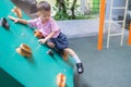 Asian 2 - 3 years old toddler child having fun trying to climb on artificial boulders at schoolyard playground, Little boy Royalty Free Stock Photo