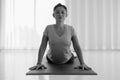 Asian yogi woman practicing yoga concept, stretching in Cobra exercise, Bhujangasana pose, working out indoor, monochrome Royalty Free Stock Photo