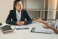 Asian young adult sitting at desk across from manager being interviewed job interview in business room