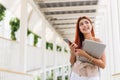 Asian young beautiful businesswoman happy smiling holding smartphone and laptop. Royalty Free Stock Photo