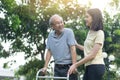 Asian young beautiful girl daughter take care of disabled senior elderly grandfather in garden. Attractive woman help and support Royalty Free Stock Photo