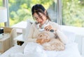 Asian young beautiful teenager girl owner in turtleneck sweater wearing headphones listening to music smiling on the bed Brush cat Royalty Free Stock Photo
