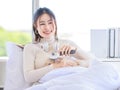 Asian young beautiful teenager girl owner in turtleneck sweater wearing headphones listening to music smiling on the bed Brush cat Royalty Free Stock Photo