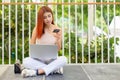 Asian young beautiful woman red hair sitting on floor with laptop computer with holding credit card. Royalty Free Stock Photo