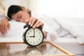 Asian young beauty woman turning off alarm clock in morning late without looking clock and lazy to working on in holiday. Bedroom Royalty Free Stock Photo