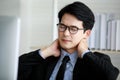 Asian young black short hair male employee worker wears formal suit with necktie gray shirt and eyeglasses has office syndrome