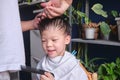 Asian young boy getting a haircut at home, Father makes a haircut for his son with scissors. Home haircut while in quarantine Royalty Free Stock Photo