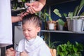 Asian young boy getting a haircut at home, Father makes a haircut for his son with scissors. Home haircut while in quarantine Royalty Free Stock Photo