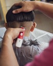 Asian young boy is getting haircut at home using electric razor. view from behind Royalty Free Stock Photo