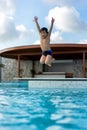 Asian Young Boy Having a good time in swimming pool, He Jumping and Playing a Water in Summer
