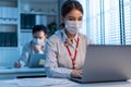 Asian young business woman wear mask, feel tired from work in office. Man and woman employee worker use computer on table overwork Royalty Free Stock Photo
