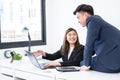 Asian young businesswoman wear formal suit working with colleagues man presenting new ideas on laptop with smiling face Royalty Free Stock Photo