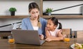 Asian young cheerful female mother and little cute girl daughter sitting smiling watching streaming movie online via laptop Royalty Free Stock Photo