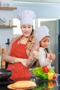 Asian young cheerful female mother and little cute girl daughter wearing white tall cook hat and apron standing crossed arms Royalty Free Stock Photo