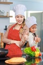 Asian young cheerful female mother and little cute girl daughter wearing white tall cook hat and apron standing crossed arms Royalty Free Stock Photo