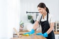 Asian young cleaning service woman worker clean kitchen table at home. Beautiful young girl housekeeper cleaner feel happy and Royalty Free Stock Photo