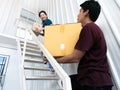 Asian young couple girl and boy carrying and holding heavy cardboard and small parcel box upstairs to their room after moving to Royalty Free Stock Photo