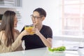 Asian young couple holding a glass of fresh orange juice for health with vegetable salad, laptop, and a smartphone Royalty Free Stock Photo