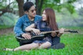 asian young couple in love looking and embracing each other and sitting relax enjoy playing guitar in the park . boyfriend Royalty Free Stock Photo