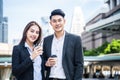 Asian young couple office business people stand outdoor in city with confident face holding hot coffee. Working man and woman feel Royalty Free Stock Photo