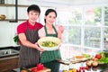 Asian young couple`s smiling, happiness in apron, make cooking together in kitchen. Showing big bowl of vegetable salad. there ar Royalty Free Stock Photo