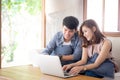 Asian young couple using laptop computer think and searching internet together, man and woman casual smiling work at home Royalty Free Stock Photo