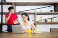 Asian Young couple,Woman are looking business in laptop and behind have a man talking mobile phone Royalty Free Stock Photo
