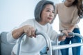 Asian young daughter support old disabled woman walk with walker at home. Beautiful girl help and take care of senior elderly Royalty Free Stock Photo