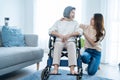 Asian young daughter support older senior woman on wheelchair at home. Beautiful girl granddaughter help and take care of elderly Royalty Free Stock Photo