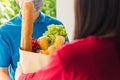 Delivery man wear protective face mask making grocery giving fresh food to woman customer Royalty Free Stock Photo