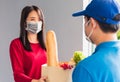 Delivery man wear protective face mask making grocery giving fresh food to woman customer Royalty Free Stock Photo